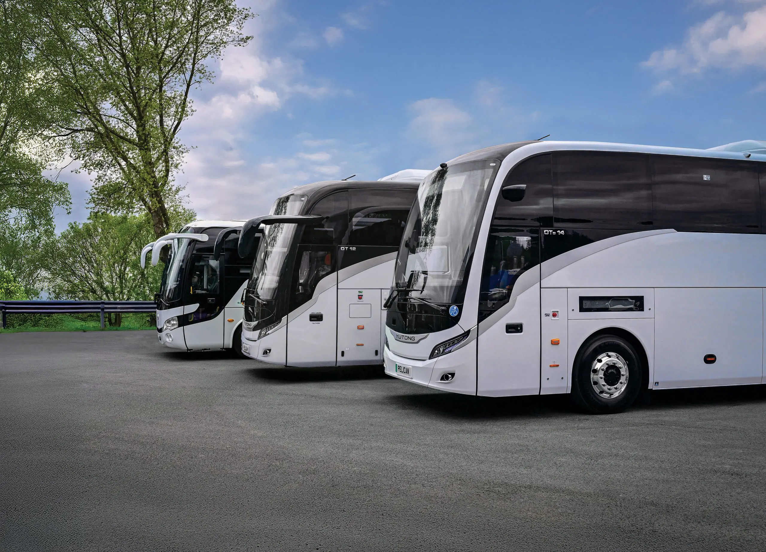 Three White Yutong coaches , a GT12, A TC9 and. GTE14 all parked in a car park with sceneic blue sky in the background.